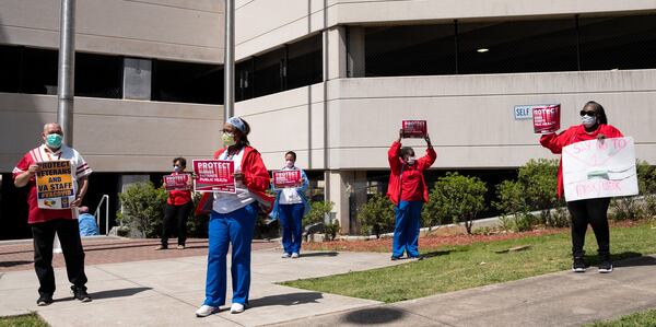 In a protest organized by the National Nurses United union, a group of nurses and their supporters held up signs for passing cars outside of the Atlanta VA Medical Center on Friday. One sign said, “Say no to 1 mask/week.” Ben@BenGray.com for the Atlanta Journal-Constitution