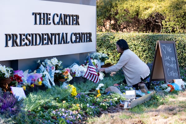 Jansen Head of Woodstock places a rosary on a makeshift memorial outside the Carter Center earlier this week.