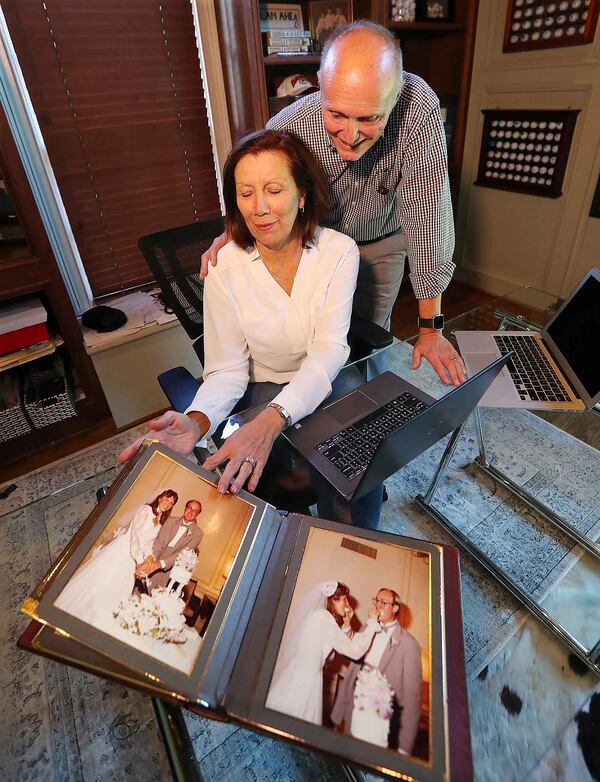 Doug and Marketia Patterson show off their wedding album while working in their home office on Tuesday, October 24, 2017, in Milton. The Patterson's insurer, Blue Cross, responded to federal cuts to Obamacare supports by dropping its metro Atlanta individual plans entirely. So Doug and Marketia, who had a Blue Cross individual plan, were without an acceptable health insurance policy for 2018. Advisers told them there was one solution: since they owned their own business together, they could get a group plan -- if they would divorce. They just celebrated their 35th wedding anniversary.