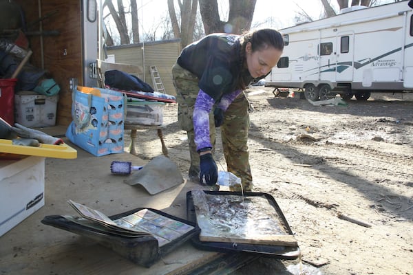 Jill Holtz pours water over what she said was a canvas family portrait she found that she hadn'tcleaned yet on Thursday, Feb. 6, 2025, in Swannanoa, N.C. (AP Photo/Makiya Seminera)