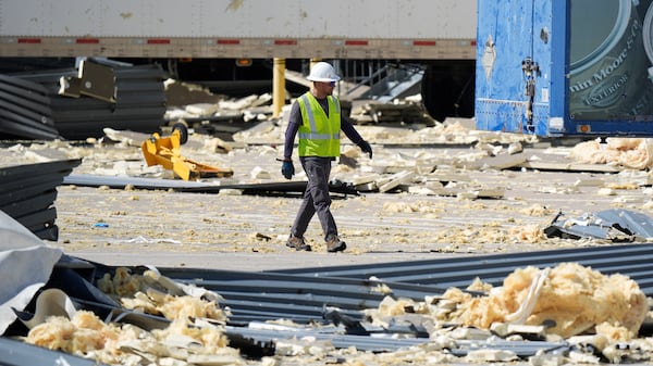 A worker walks through debris from a damaged warehouse after storms moved through Tuesday, March 4, 2025, in Lewisville, Texas. (AP Photo/LM Otero)