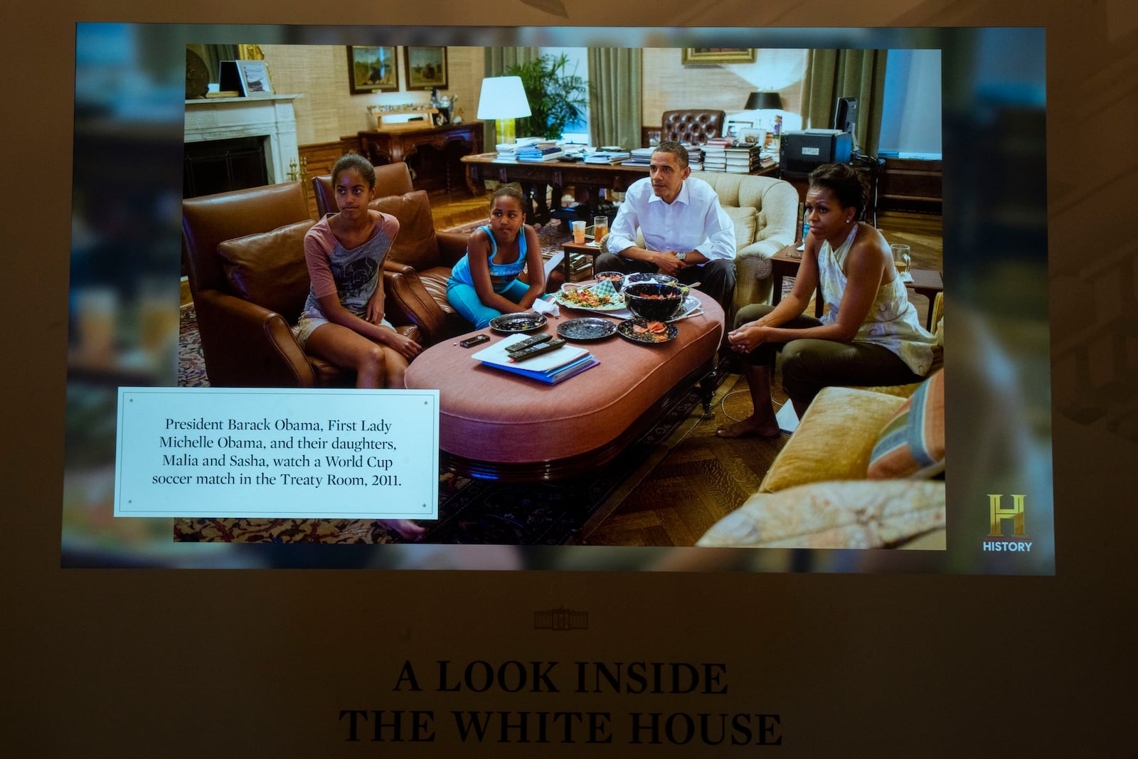 "A look inside the White House" digital frame that changes picture display every minute, shows on Friday, Oct. 18, 2024 in Washington, a captioned picture of former President Barack Obama and his family in the Treaty Room. (AP Photo/Manuel Balce Ceneta)