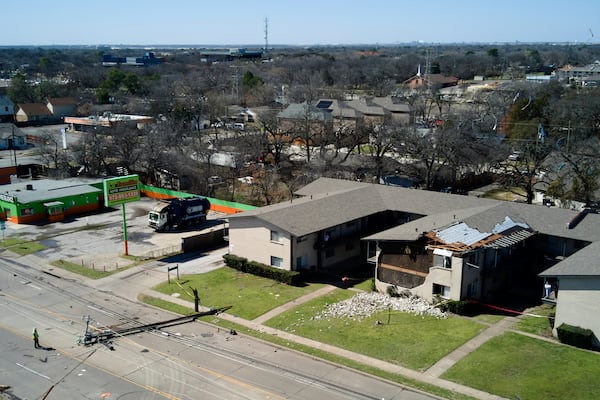 A downed power line rests on the road near an apartment building damaged during early morning storm that hit the Dallas region Tuesday, March 4, 2025, in Irving, Texas. (AP Photo/Julio Cortez)