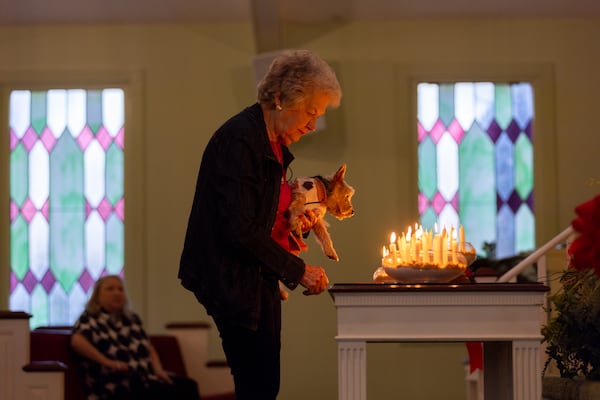 Nelle Ariail, with her dog Lizzie, lights a candle at Maranatha Baptist Church during a vigil for former President Jimmy Carter in Plains on Monday, December 30, 2024, a day after Carter died at the age of 100. (Arvin Temkar / AJC)