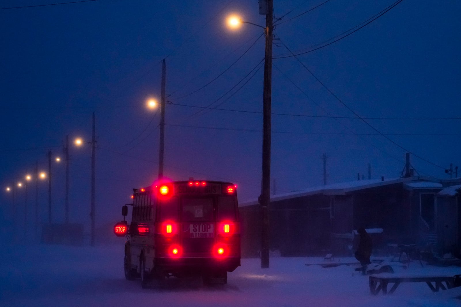 A child walks to the village's school bus as a blizzard blows outside in Kaktovik, Alaska, Thursday, Oct. 17, 2024. (AP Photo/Lindsey Wasson)