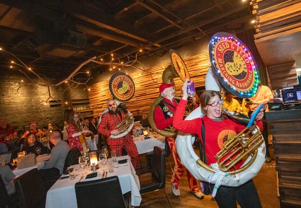 The Seed and Feed Marching Abominable Band, including tuba player Mureen Kumpf, gathers for a blitz on the Beltline earlier this month and marches through Rathbun Steak at owner Kevin Rathbun’s invitation in the flash mob-like performance.  (Jenni Girtman for The Atlanta Journal-Constitution)