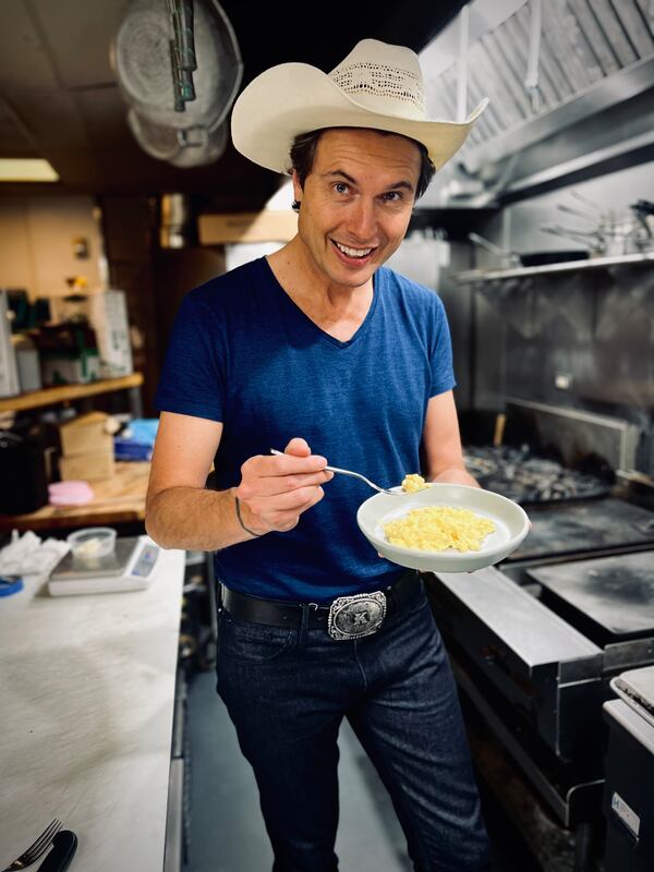 Kimbal Musk samples a dish inside a restaurant kitchen.