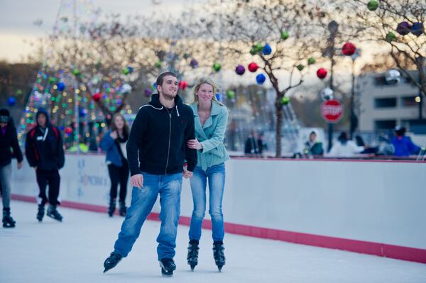 Anthony Keith (left) holds hands with Hannah Shuler as they ice skate at Atlantic Station in Atlanta during the annual Christmas tree lighting as thousands of people watch the show on Nov. 23, 2013.