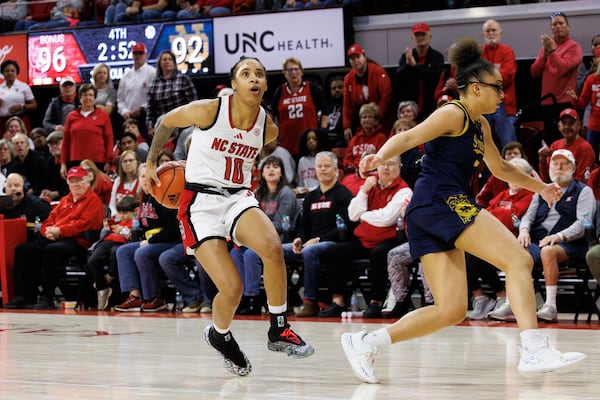 NC State's Aziaha James (10) brings the ball behind her back to beat Notre Dame's Olivia Miles, right, for a layup during the second overtime of an NCAA college basketball game in Raleigh, N.C., Sunday, Feb. 23, 2025. (AP Photo/Ben McKeown)