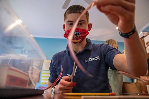 Asher Williams cuts a piece of evidence tape for Georgia Bureau of Investigation Crime Scene Specialist Daniella Stuart during one of his classes at ClearWater Academy in Tyrone on Tuesday, May 4, 2021. ClearWater Academy is a school for students with special needs. (Alyssa Pointer / Alyssa.Pointer@ajc.com)