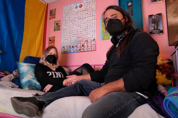 Steve Alejandro and his wife, Ashley, sit for a portrait in the room where Ashley spends most of her time due to illness, in the basement of their home Wednesday, Dec. 18, 2024, in Wentzville, Mo. (AP Photo/Jeff Roberson)