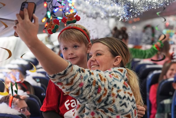 Kaelee Thomas, right, takes a selfie with her 7-year-old son, Greyson, before take off during the United Airlines annual "fantasy flight" to a fictional North Pole at Denver International Airport, Saturday, Dec. 14, 2024, in Denver. (AP Photo/David Zalubowski)