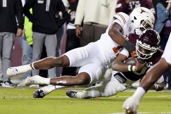 Texas linebacker Colin Simmons, top, tackles Texas A&M quarterback Marcel Reed, bottom, short of the goal line during the second half of an NCAA college football game Saturday, Nov. 30, 2024, in College Station, Texas. (AP Photo/Sam Craft)