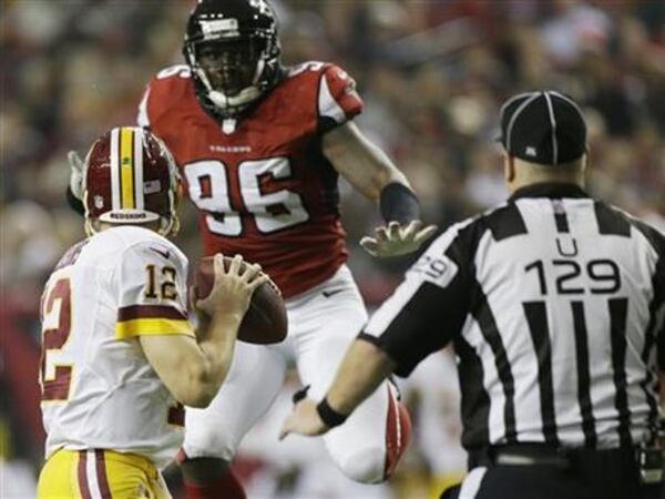 Washington Redskins quarterback Kirk Cousins (12) works under pressure from Atlanta Falcons defensive end Jonathan Massaquoi (96) during the second half of an NFL football game, Sunday, Dec. 15, 2013, in Atlanta. (AP Photo/John Bazemore)