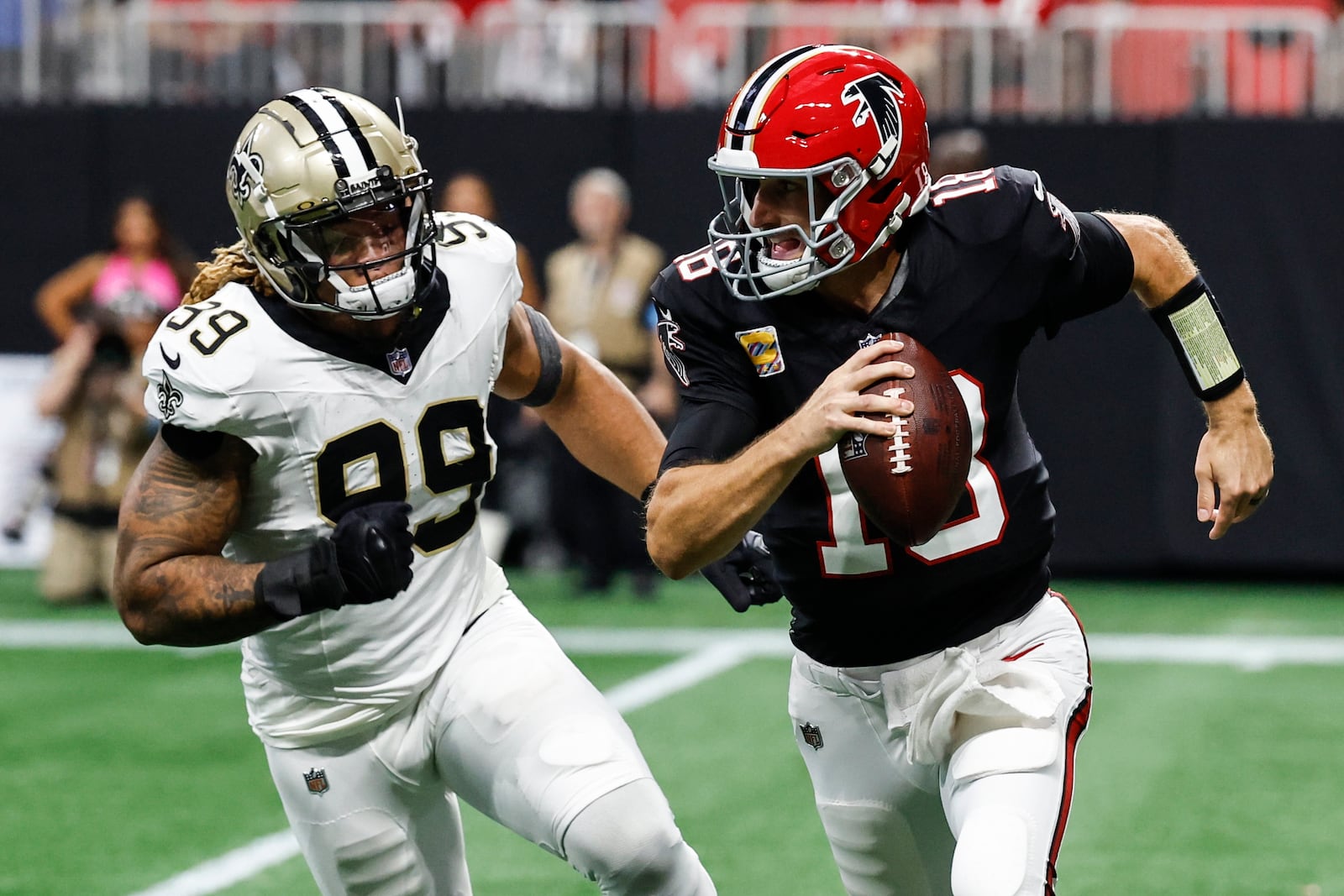 Atlanta Falcons quarterback Kirk Cousins (18) runs out of the pocket against New Orleans Saints defensive end Chase Young (99) during the second half of an NFL football game, Sunday, Sept. 29, 2024, in Atlanta. (AP Photo/Butch Dill)