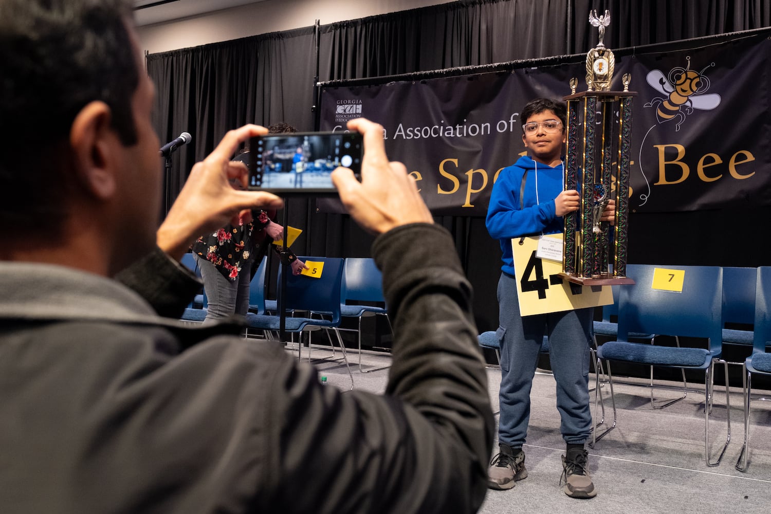 Shailesh Dharavane takes photo of his son Sarv after he won the GAE State Spelling Bee Championship at Georgia State University in Atlanta on Friday, March 21, 2025.   Ben Gray for the Atlanta Journal-Constitution