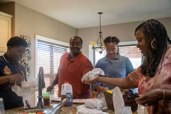 Samanthia Jordan-Hill, from right, her daughter Kristen Jordan, her husband, Norman Hill, and her adopted son, Christian Jordan, prepare their lunch Wednesday at their residence in Newnan. Jordan-Hill learned about Christian through the "Wednesday's Child" program, a partnership between the Georgia Division of Children and Family Services and local media to highlight children in foster care and encourage adoption. (Alyssa Pointer / Alyssa.Pointer@ajc.com)