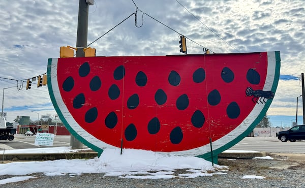 A giant plywood watermelon on a Cordele street corner sits atop remnants of snow on Thursday, Jan. 23, 2025. (Joe Kovac Jr./AJC)