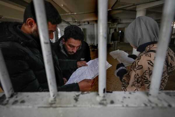 People inspects documents they found in the infamous Saydnaya military prison, just north of Damascus, Syria, Monday, Dec. 9, 2024. Crowds are gathering to enter the prison, known as the "human slaughterhouse," after thousands of inmates were released following the rebels' overthrow of Bashar al-Assad's regime on Sunday. (AP Photo/Hussein Malla)