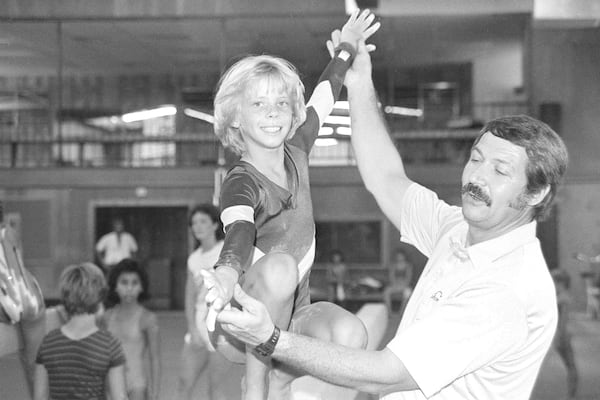 FILE - Olympic gymnastics coach Bela Karolyi, right, instructs Sara Tank on the balance beam at his Olympic training facility in north Houston, Aug. 12, 1985. (AP Photo/Richard J. Carson, File)