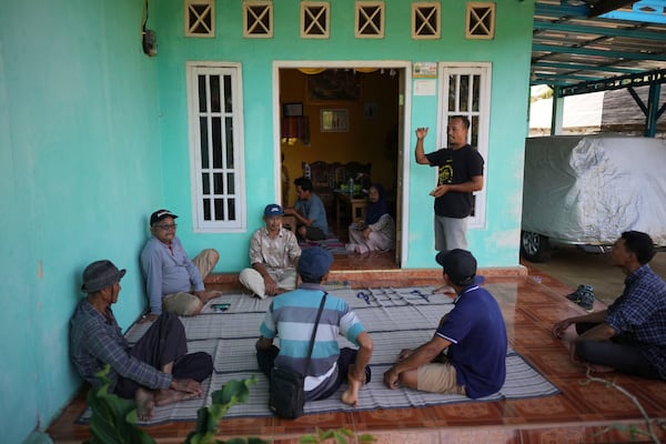 Cocoa farmer Sarwono, right, speaks during a cocoa farmer's cooperative meeting at his house in Tanjung Rejo, Lampung province, Indonesia, Wednesday, Feb. 19, 2025. (AP Photo/Dita Alangkara)