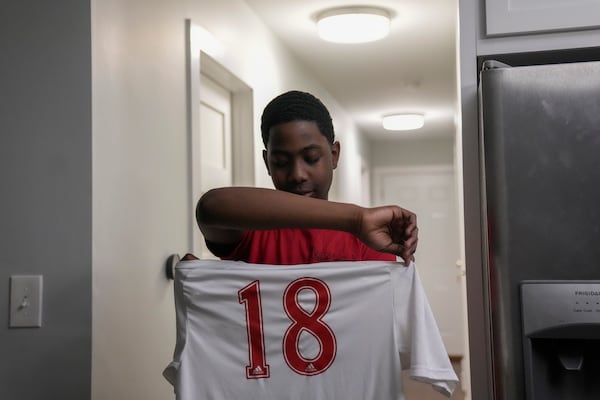 Josafat, 14, an immigrant from Central America seeking asylum, proudly displays his soccer jersey at his family's home Thursday, Feb. 20, 2025, in Chicago. (AP Photo/Erin Hooley)