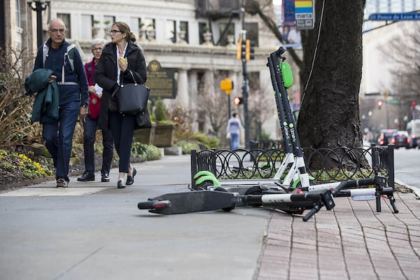 01/04/2019 — Atlanta, Georgia — Pedestrians walk passed Lime and Bird scooters that are parked on the sidewalk of Peachtree Street in Atlanta’s Midtown community, Friday, January 4, 2019. (ALYSSA POINTER/ALYSSA.POINTER@AJC.COM)