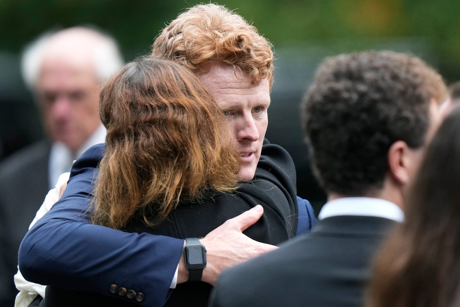 Joseph Kennedy III, center right, grandson of Ethel Kennedy, hugs fellow mourners following funeral services at Our Lady of Victory church for Ethel Kennedy, Monday, Oct. 14, 2024, in Centerville, Mass. (AP Photo/Steven Senne)