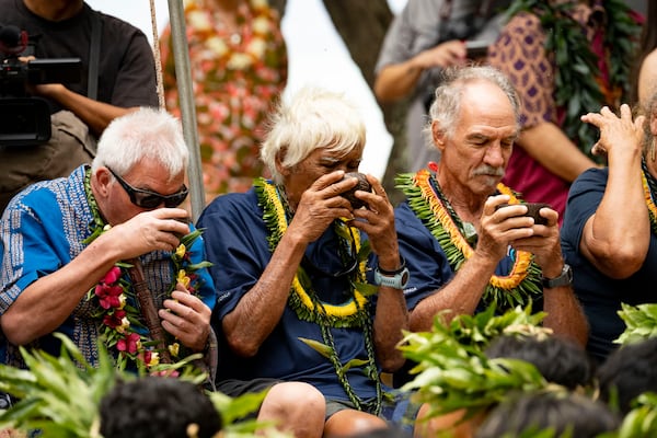 Abraham "Snake" Ah Hee, a member of Hokulea's first return trip from Tahiti to Hawaii in 1976, center, drinks an 'Award or kava, during Hokulea's 50th birthday commemoration at Kualoa Regional Park, Saturday, March 8, 2025, in Kaneohe, Hawaii. (AP Photo/Mengshin Lin)