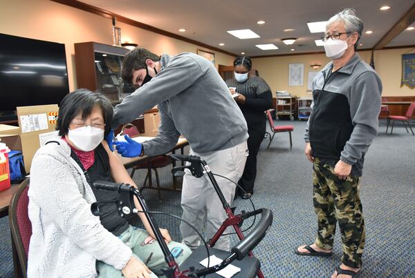 February 19, 2021 Decatur - A resident of AHEPA One Senior Apartments Bok Lee receives a first dose of the Moderna vaccine from Pharmacist Demetrios Gavalas as her husband Jong Lee (right) looks on at AHEPA One Senior Apartments in Decatur on Friday, February 19, 2021. (Hyosub Shin / Hyosub.Shin@ajc.com)