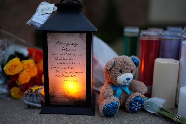 Flowers and candles are placed outside the Abundant Life Christian School Tuesday, Dec. 17, 2024 in Madison, Wis., following a shooting on Monday. (AP Photo/Nam Y. Huh)