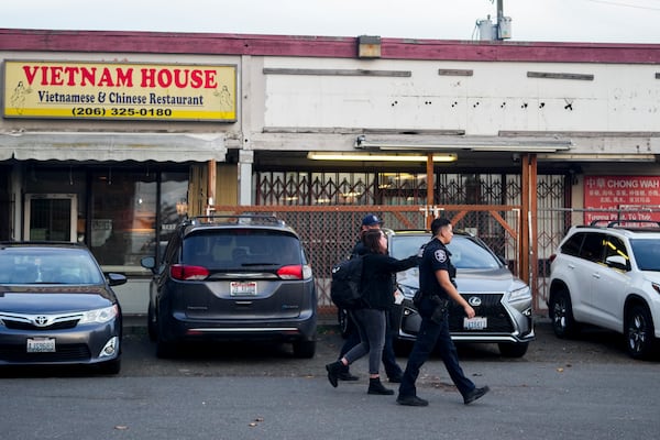 Police officers gather security camera footage from nearby businesses after multiple people were stabbed earlier in the area Friday, Nov. 8, 2024, in the Chinatown-International District in Seattle. (AP Photo/Lindsey Wasson)