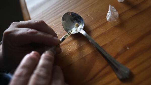 A heroin user prepares to inject himself.  