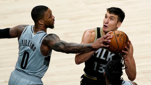 Hawks guard Bogdan Bogdanovic (13) is defended by Blazers guard Damian Lillard (0) as he tries to shoot in the first half of an NBA basketball game Monday, May 3, 2021, in Atlanta.