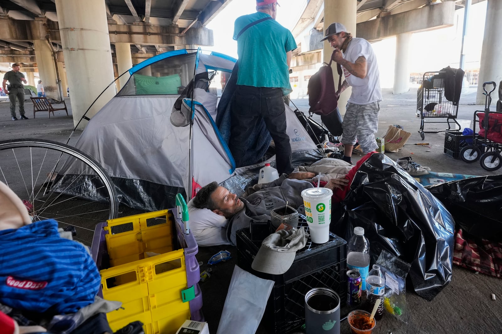 People living in a homeless encampment pick up belongings after Louisiana State police gave instructions for them to move to a different pre-designated location as they perform a sweep in advance of a Taylor Swift concert in New Orleans, Wednesday, Oct. 23, 2024. (AP Photo/Gerald Herbert)