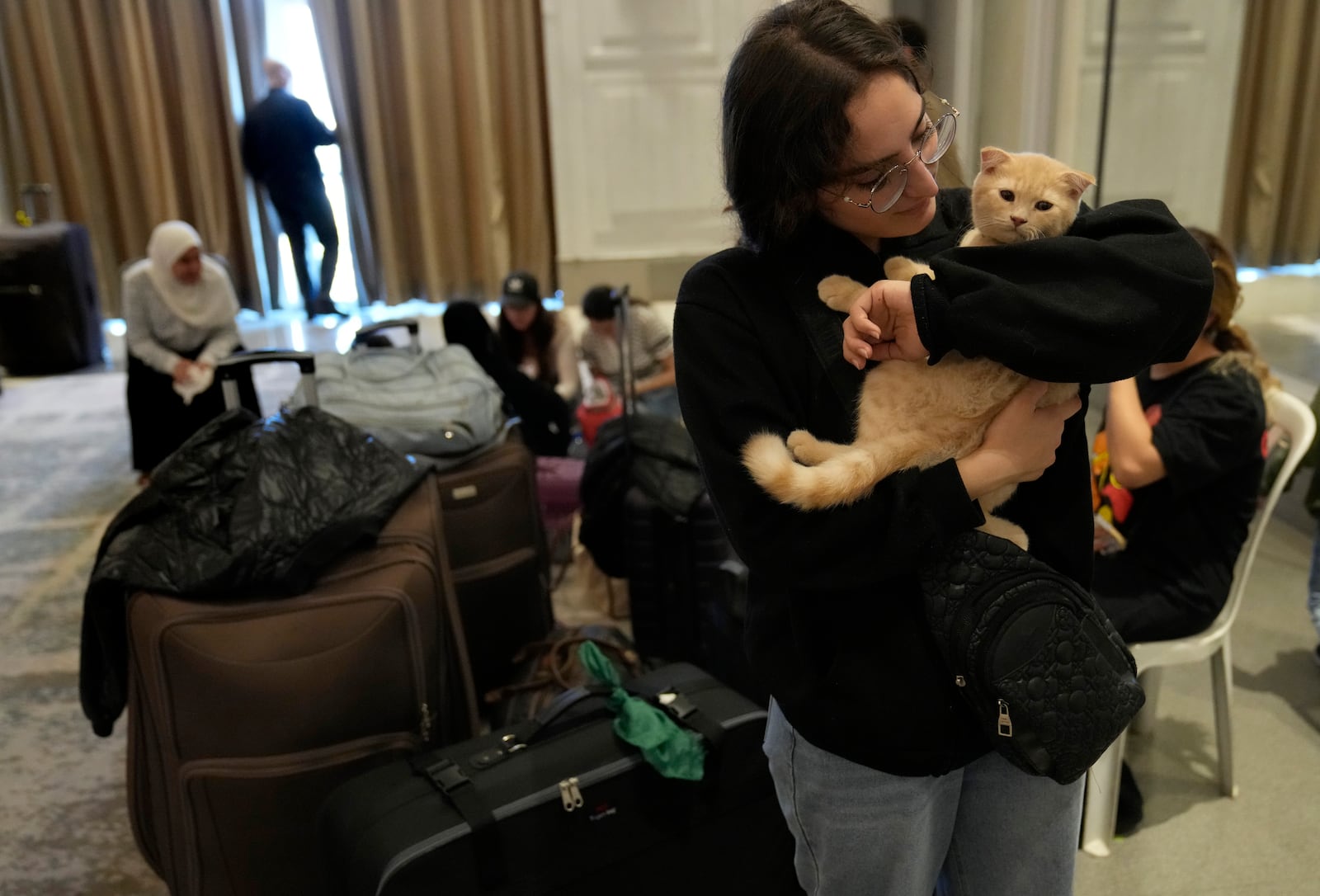 A Turkish citizen hugs her cats as she waits at a gathering point to board a Turkish navy vessel before being evacuated to Turkey, in Beirut, Lebanon, Wednesday, Oct. 9, 2024. (AP Photo/Hussein Malla)