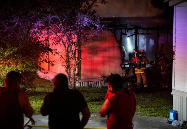 Onlookers cover their faces as smoke spreads from the fire at a mobile home park in Cobb County.