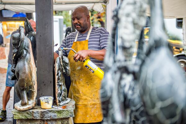 Peter Rujuwa uses a torch to make adjustments to one of his sculptures during the Chastain Park Arts Festival on Saturday, November 7, 2015. Rainy weather would not stop the two day festival featuring 185 artists. JONATHAN PHILLIPS / SPECIAL