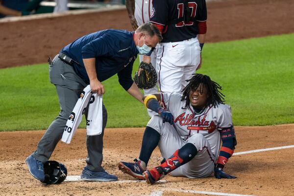 The Braves' Ronald Acuna grimaces as he is helped after fouling the ball off his left ankle during the fourth inning of a game against the  Nationals in Washington on Friday. (AP photo)