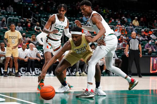 Georgia Tech forward Jordan Meka (23) lunges for a loose ball against Miami guard Kameron McGusty (23) and forward Anthony Walker during the first half Wednesday in Coral Gables, Florida. (AP Photo/Wilfredo Lee)