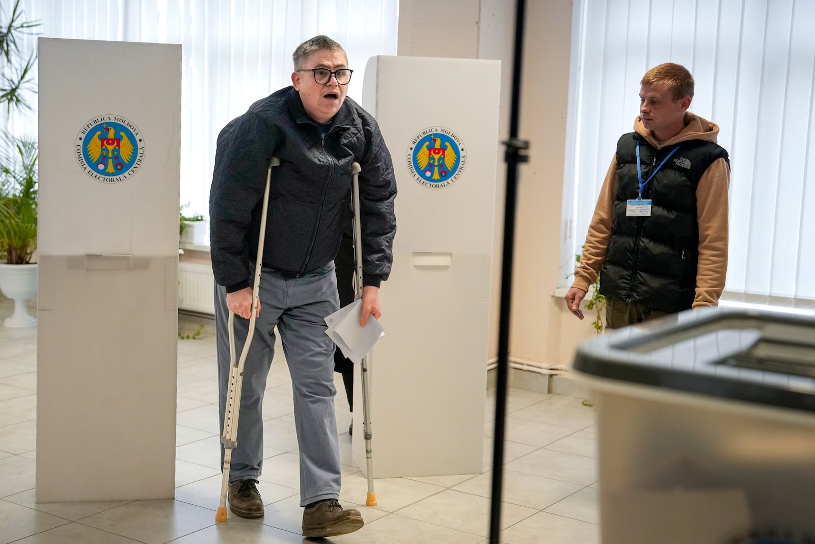 A man using crutches exits a voting booth in Chisinau, Moldova, Sunday, Oct. 20, 2024, during a presidential election and a referendum on whether to enshrine in the Constitution the country's path to European Union membership. (AP Photo/Vadim Ghirda)