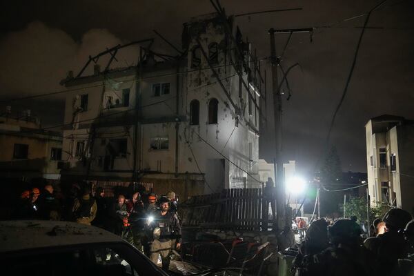 Police and rescue workers stand next to a building hit by a rocket fired from Lebanon in Shefa-Amr in northern Israel, on Monday, Nov. 18, 2024, killing a woman and injuring several others. (AP Photo/Leo Correa)