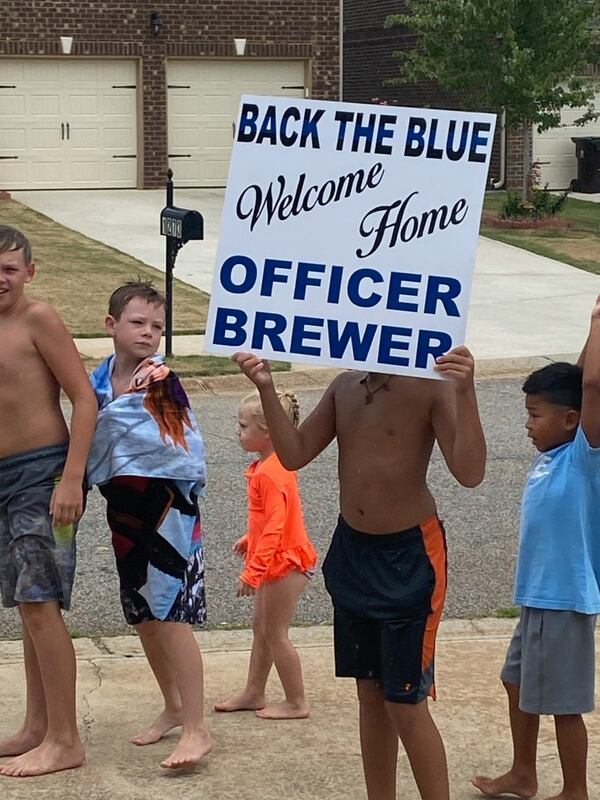 Children from Officer Max Brewer's neighborhood welcome him home Monday afternoon. Brewer spent more than a month in the hospital after being struck by an ATV.