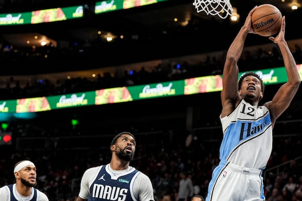 Atlanta Hawks forward De'Andre Hunter (12) shoots against Dallas Mavericks forward Naji Marshall, center, during the first half of an NBA basketball game, Monday, Nov. 25, 2024, in Atlanta. (AP Photo/Mike Stewart)