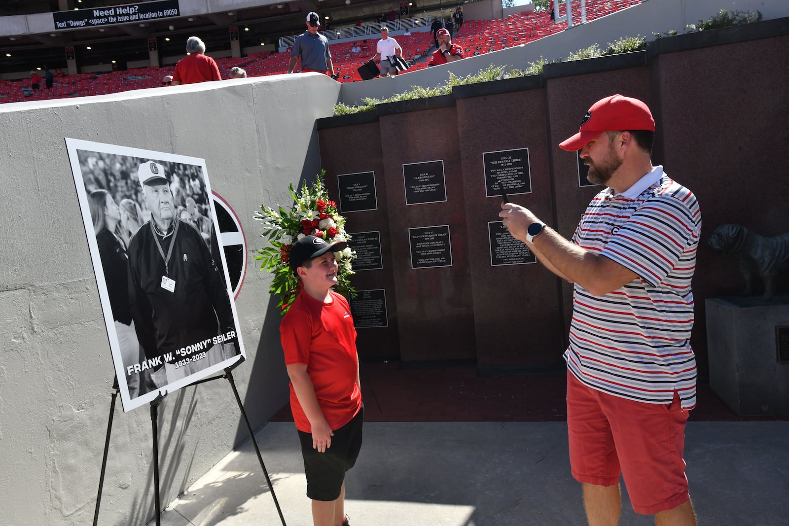 Georgia fans take their pictures in front of a memorial for the late Sonny Seiler before the home opener against UT Martin in an NCAA football game at Sanford Stadium, Saturday, September 2, 2023, in Athens. (Hyosub Shin / Hyosub.Shin@ajc.com)