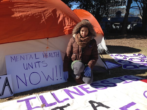 Bridget Anderson kneels at the door of one of the tents outside the DeKalb County Courthouse, where she and other activists await a grand jury decision in the death of Anthony Hill, the unarmed veteran shot and killed by police in March. Anderson was Hill’s girlfriend. GRACIE BONDS STAPLES / GSTAPLES@AJC.COM