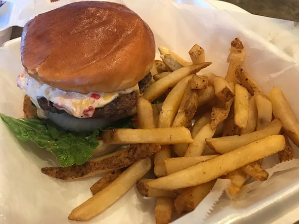 Buckeyes is the only restaurant in the small town of Jersey, Ga. The cafeteria-style restaurant, now in its 10th year, serves home-style fare for breakfast and lunch. Pictured is the Buckeyes Burger, a 6-ounce patty topped with house-made pimento cheese, bacon, lettuce, tomato, onion and pickles. LIGAYA FIGUERAS / LFIGUERAS@AJC.COM