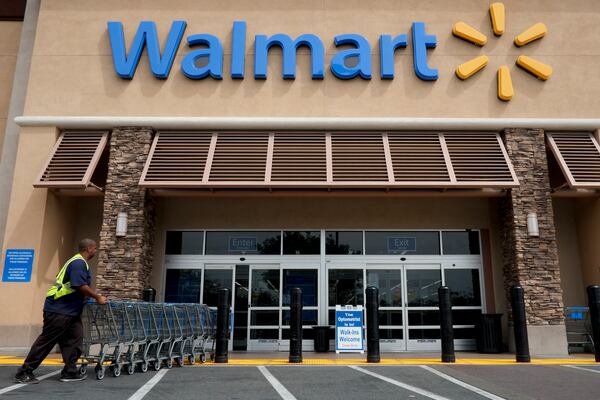 In this May 9, 2013, file photo, a worker pushes shopping carts in front of a Walmart store in La Habra, Calif. (AP Photo/Jae C. Hong, File)