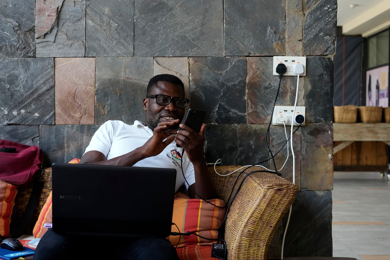 Salim Zulu, a businessman, works on his laptop and charges devices at Mercato Cafe in Lusaka, Zambia, Tuesday, Sept. 17, 2024. (AP Photo/Themba Hadebe)