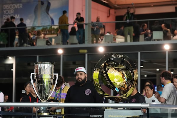 Soccer fans visit a display of the trophies for the CONCACAF Champions Cup, left, and the 2025 FIFA Club World Cup soccer tournament, ahead of a CONCACAF Champions Cup soccer match between Inter Miami and Sporting Kansas City, Tuesday, Feb. 25, 2025, in Fort Lauderdale, Fla. (AP Photo/Rebecca Blackwell)